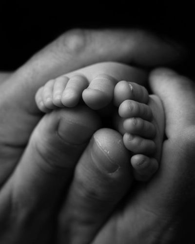 Nyf&oslash;dtfotografering - N&aelig;rbilde av t&aelig;r av nyf&oslash;dtbaby med pappas hender