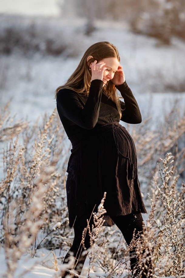 Dame med m&oslash;rke kl&aelig;r og gravidmage  i sn&oslash; og frost
