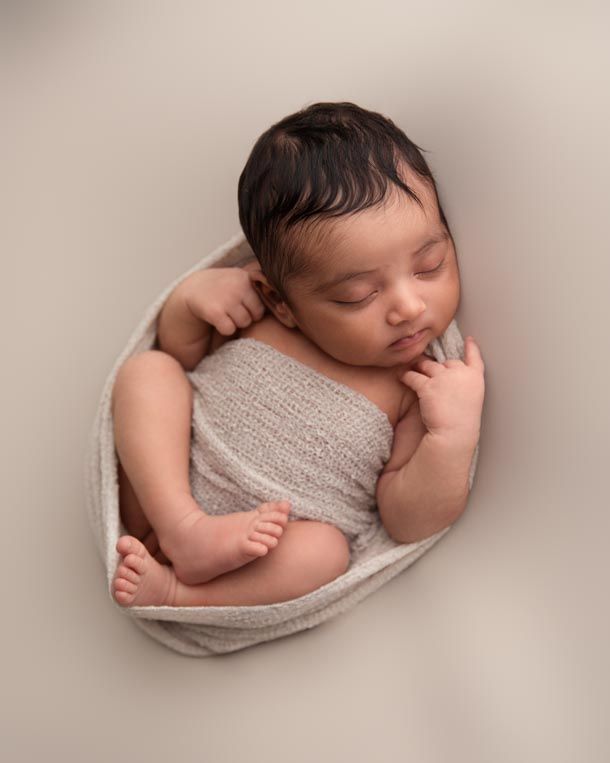 Nyf&oslash;dtfotografering - Baby som sover p&aring; beige teppe med teppe rundt seg