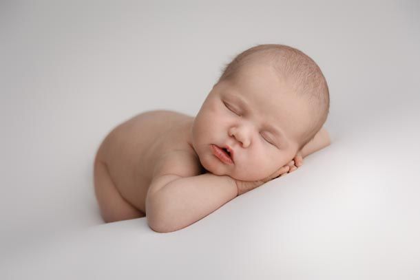 Baby sover p&aring; hendene sine p&aring; hvitt teppe i studio p&aring; Frogner