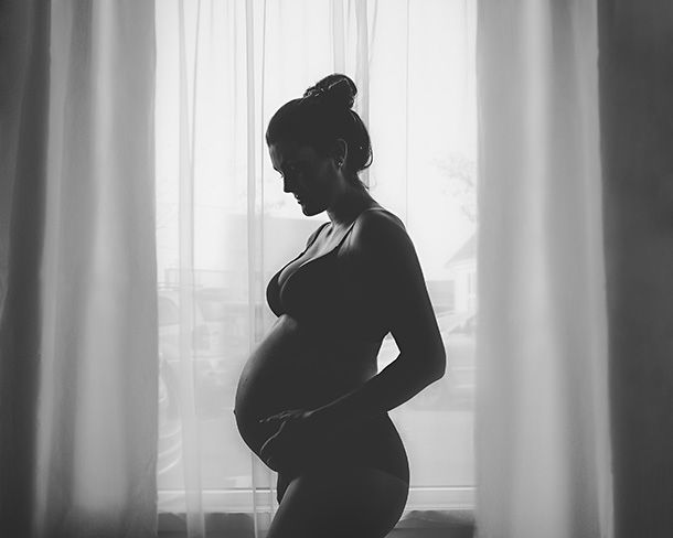 Fotografering - dame forran vindu med gravidmage i sorthvitt