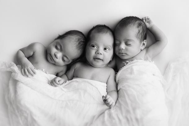 Trillinger ligger p&aring; hvitt teppe med hvitt teppe over seg