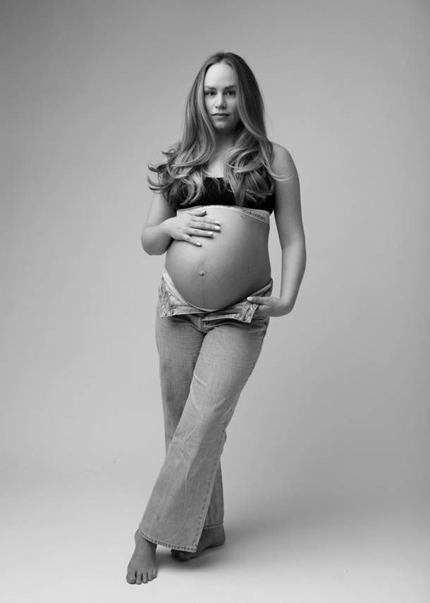 Gravid dame i jeans poserer i jeans og sort top